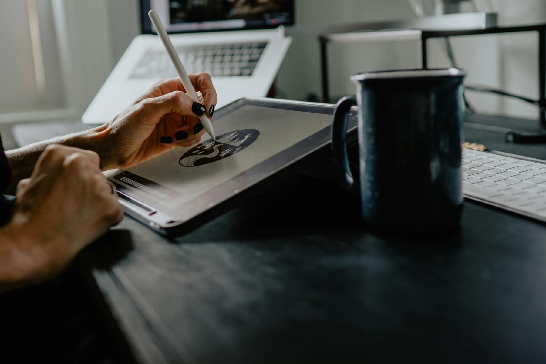 Photograph of a person drawing on a tablet at a desk.